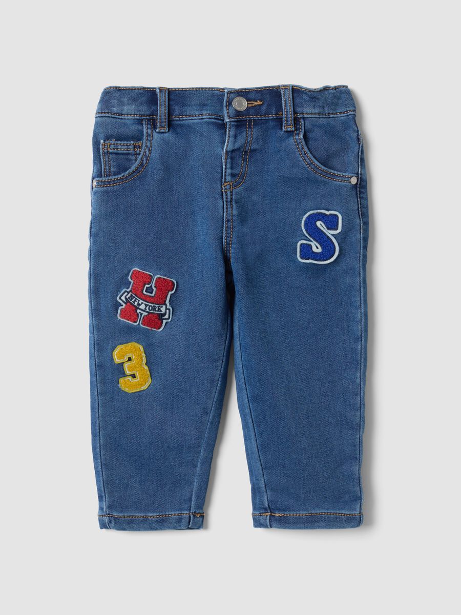 Jeans blu in cotone elasticizzato con applicazioni college per bimbo_0
