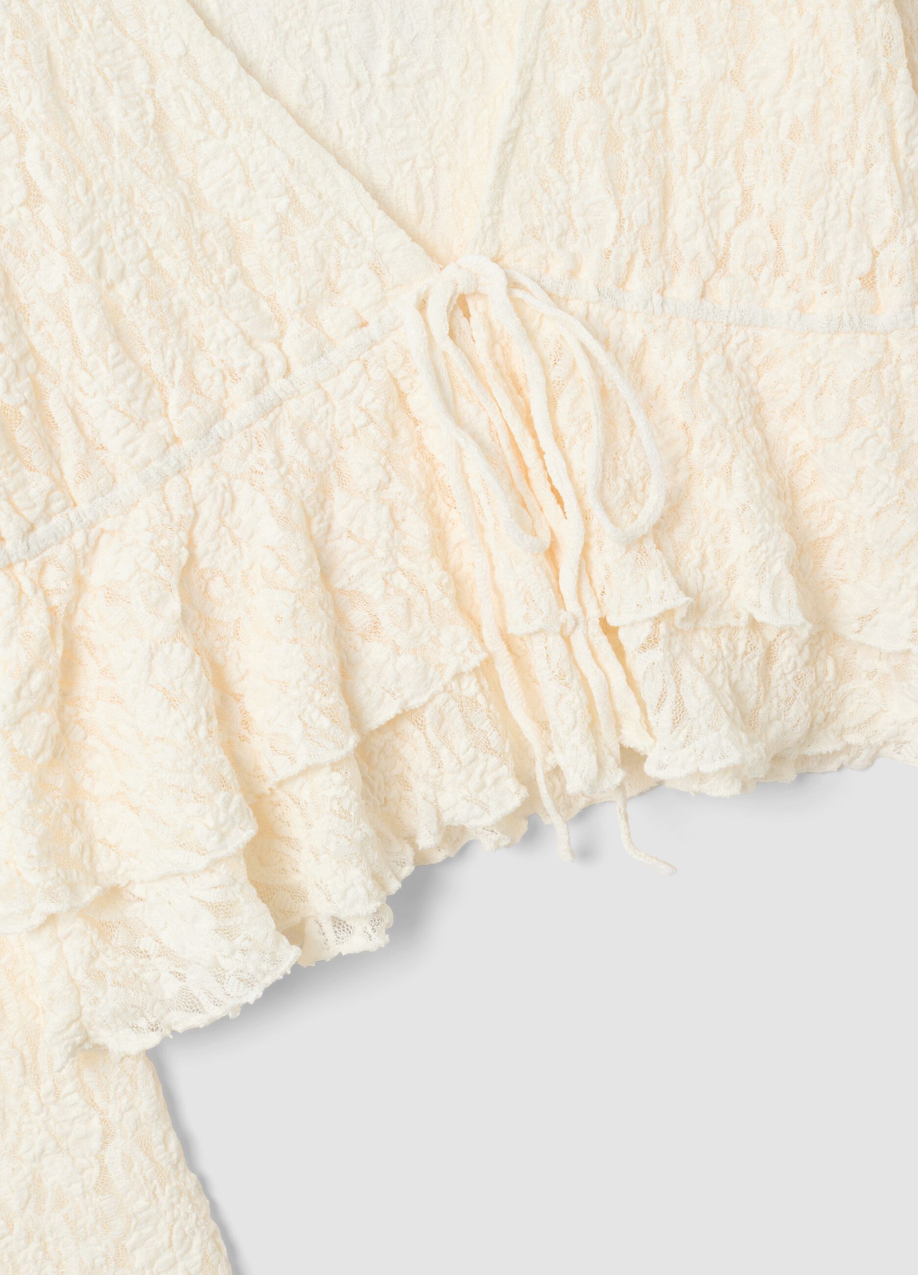 Top bianco in tessuto elasticizzato con scollo profondo a V e volant