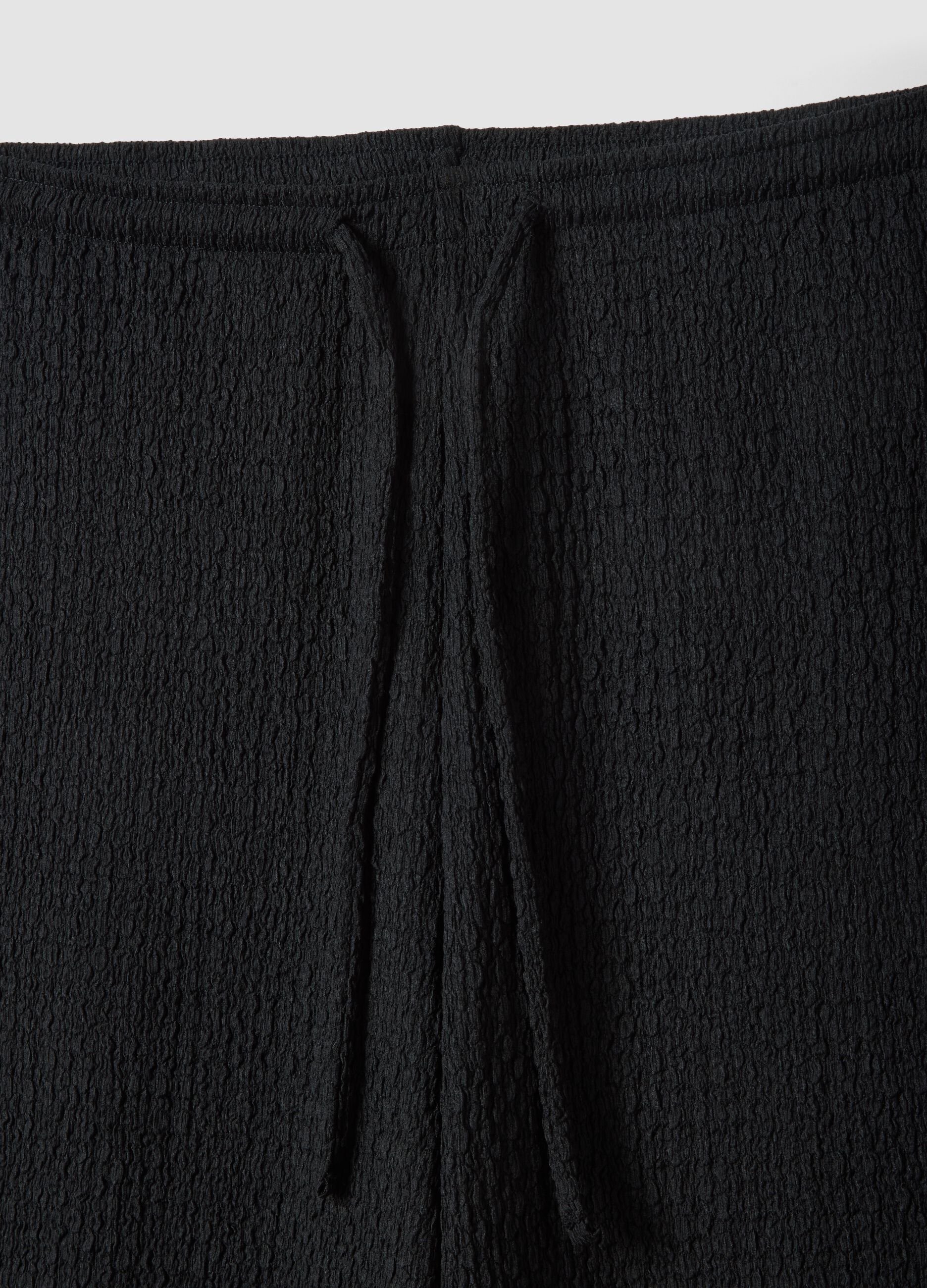 Black stretchy wide-leg trousers with crinkled texture
