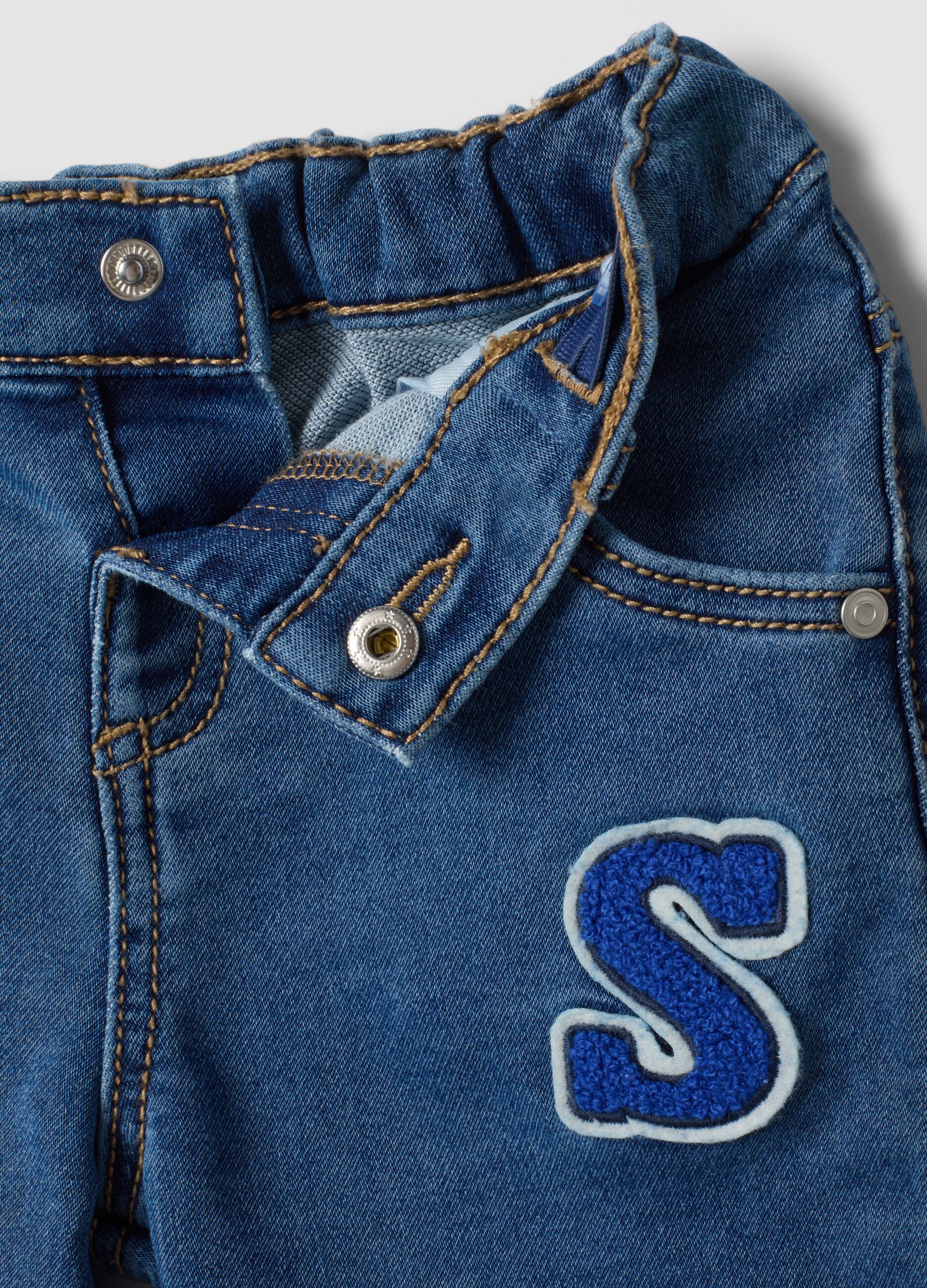 Blue stretch cotton jeans with varsity-style appliqu&eacute;s for baby boy
