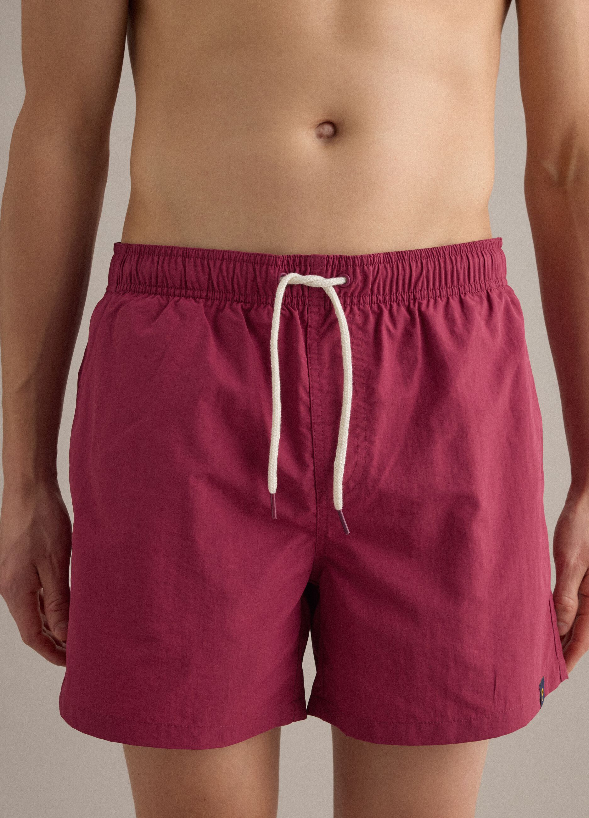 Red swim shorts with elasticated waistband and drawstring