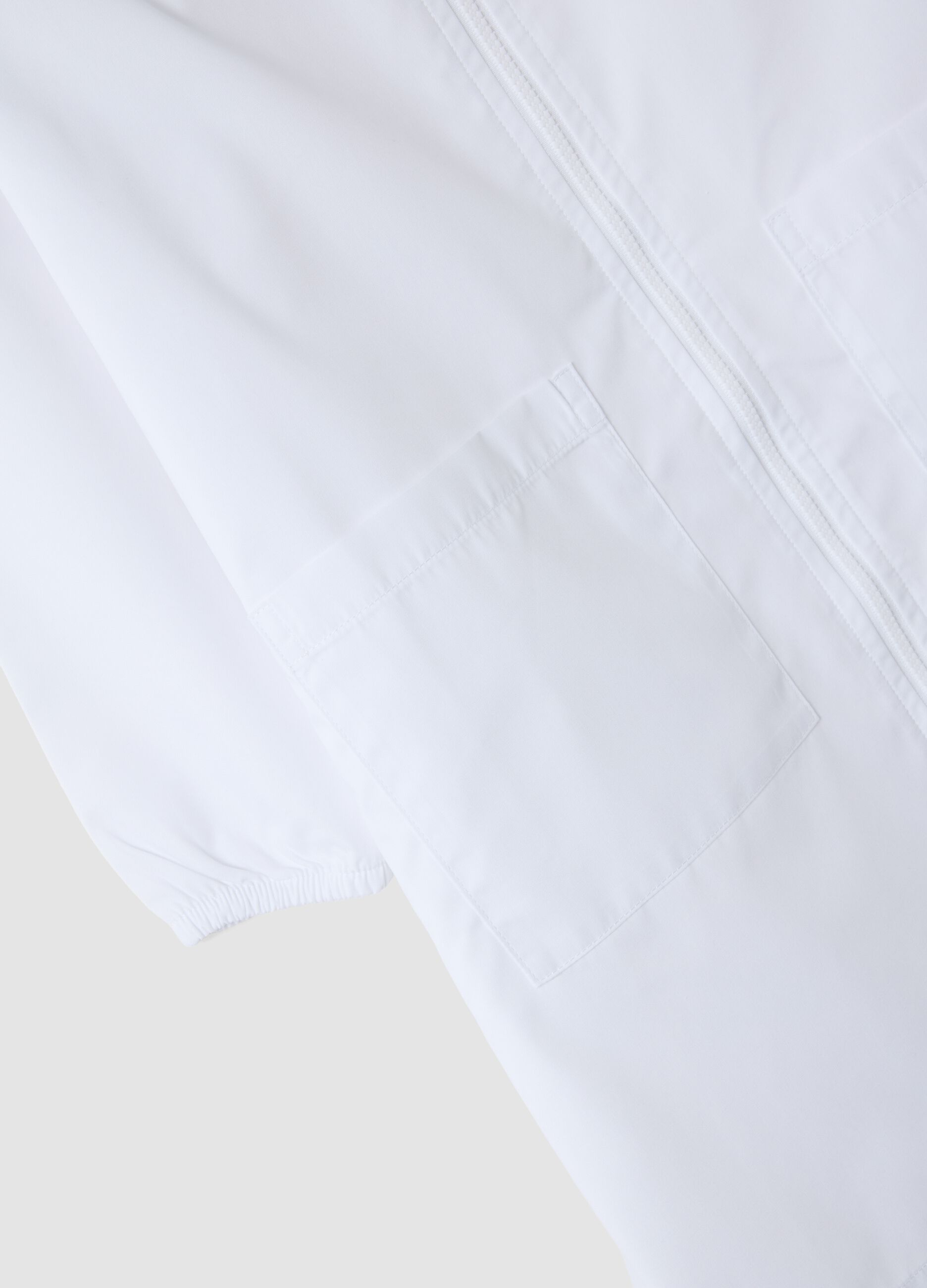 White nursery apron with zip and dinosaur embroidery for boys