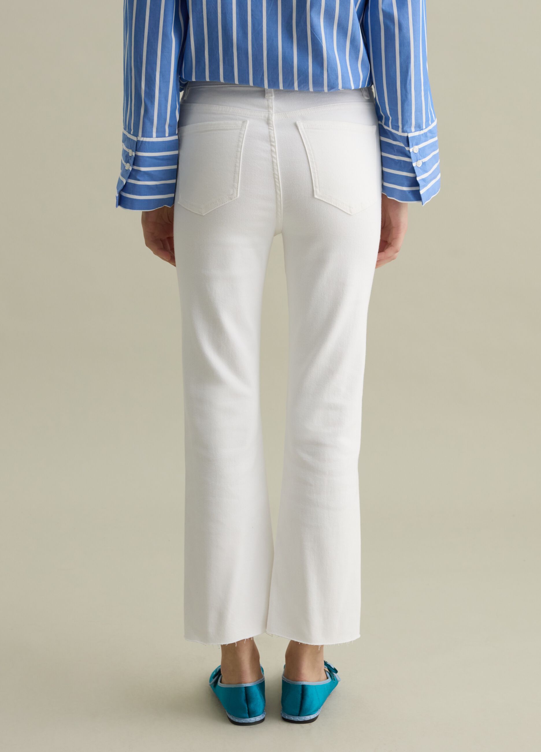 Cropped white flare-fit jeans with raw edging