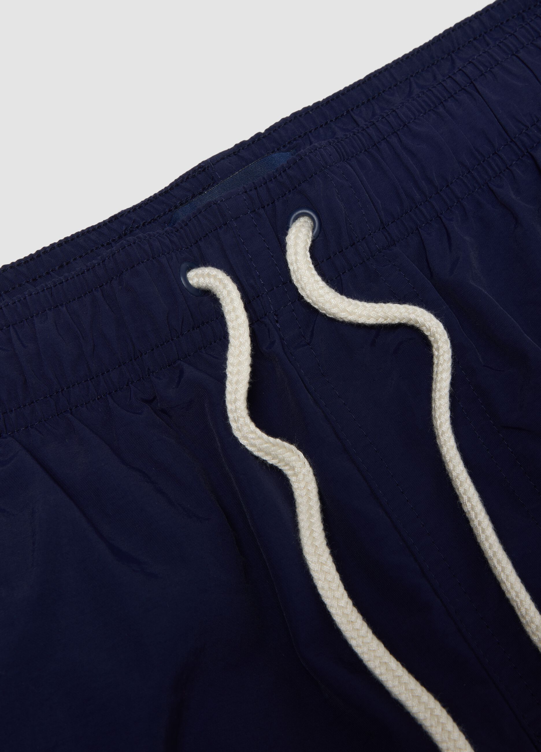 Blue swim shorts with elasticated waistband and drawstring