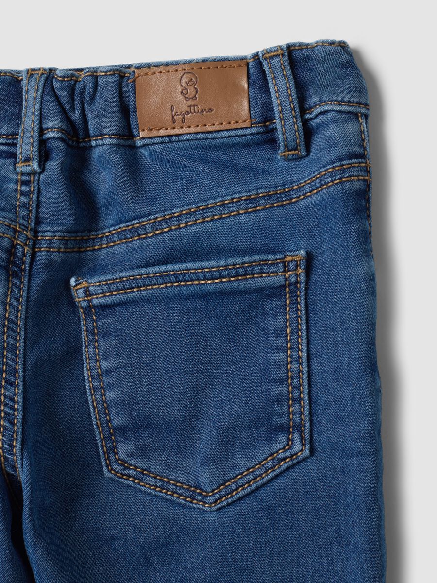 Jeans blu in cotone elasticizzato con applicazioni college per bimbo_3