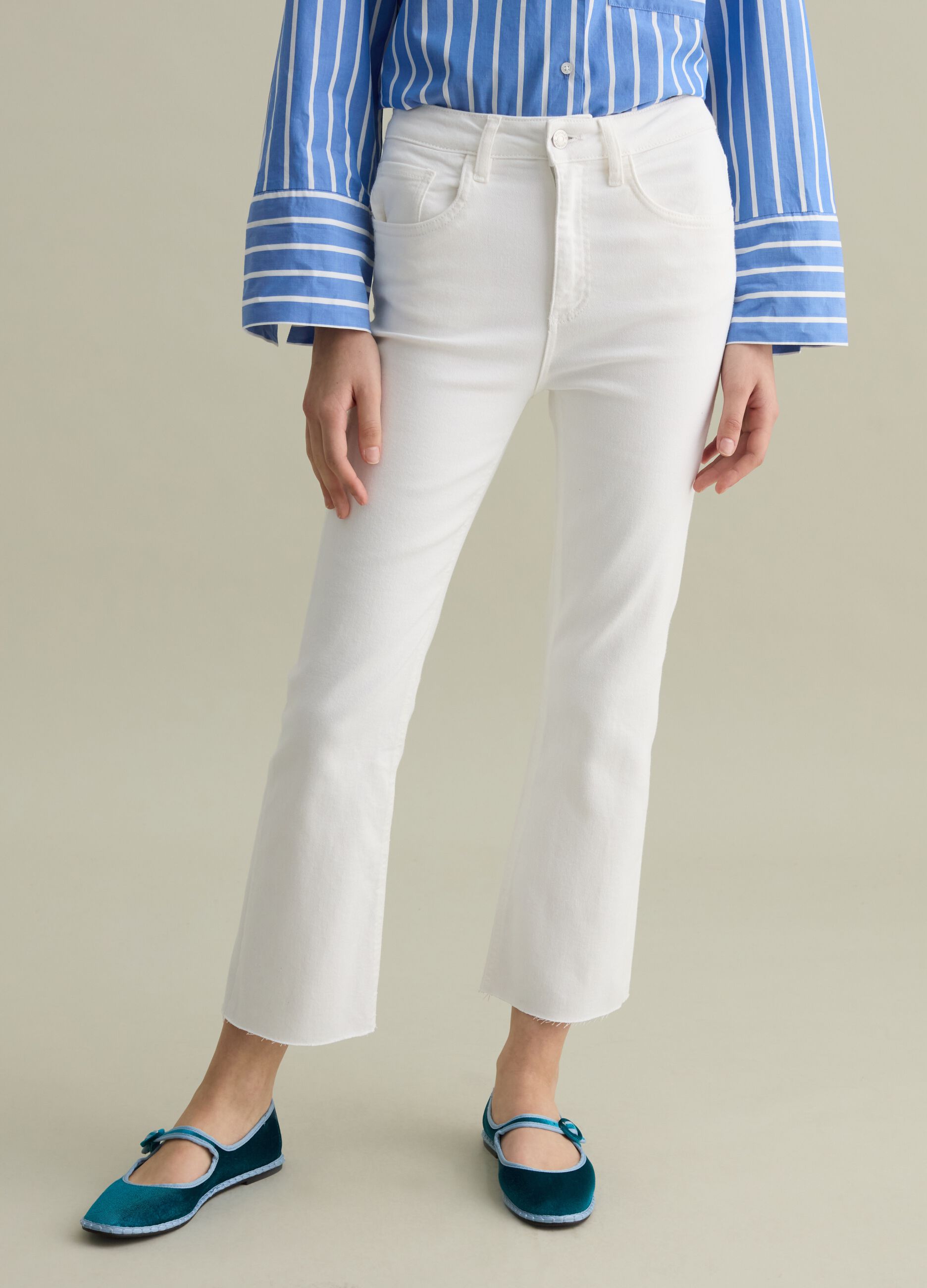 Cropped white flare-fit jeans with raw edging