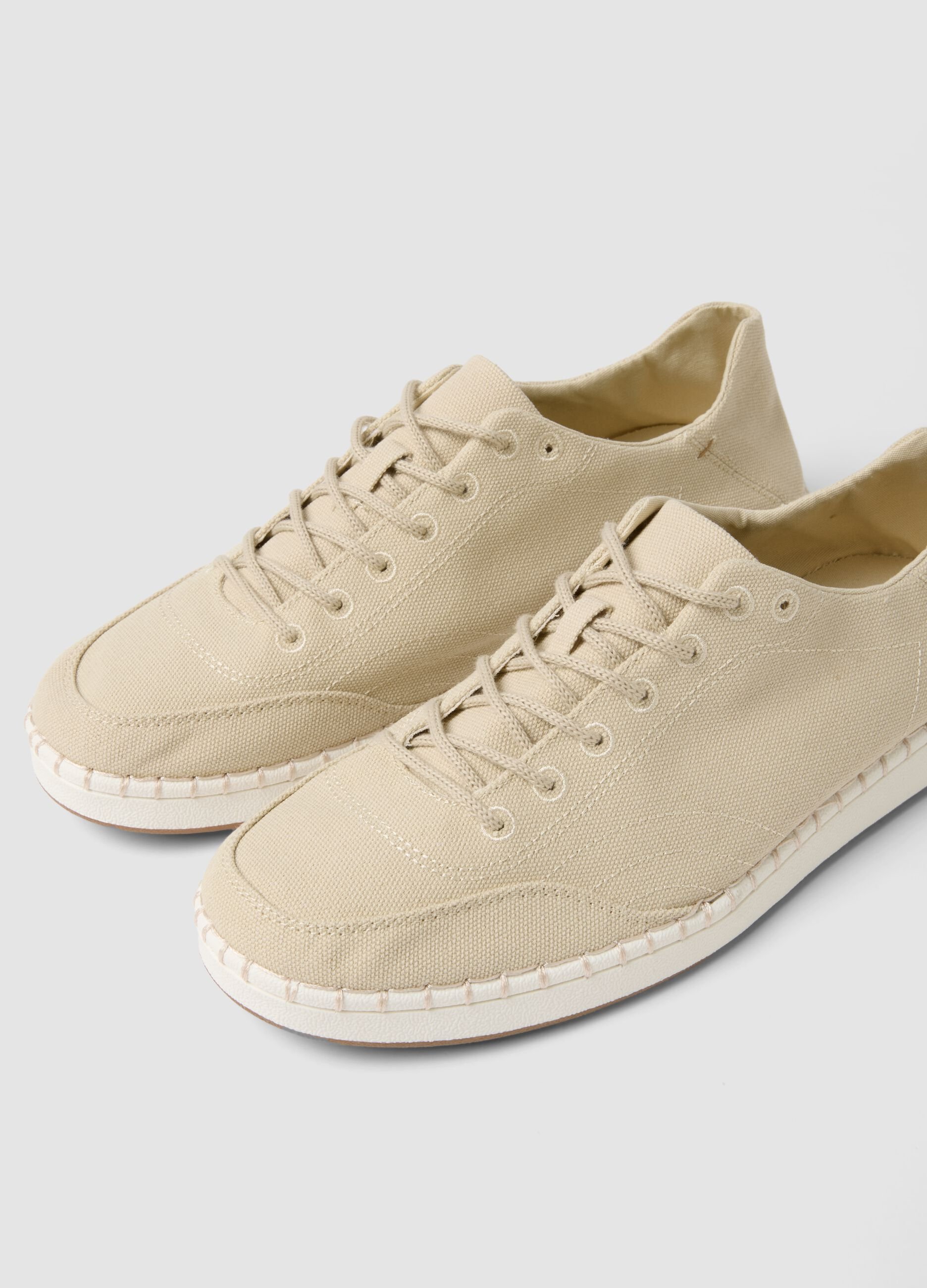 Beige lace-up trainers with visible stitching