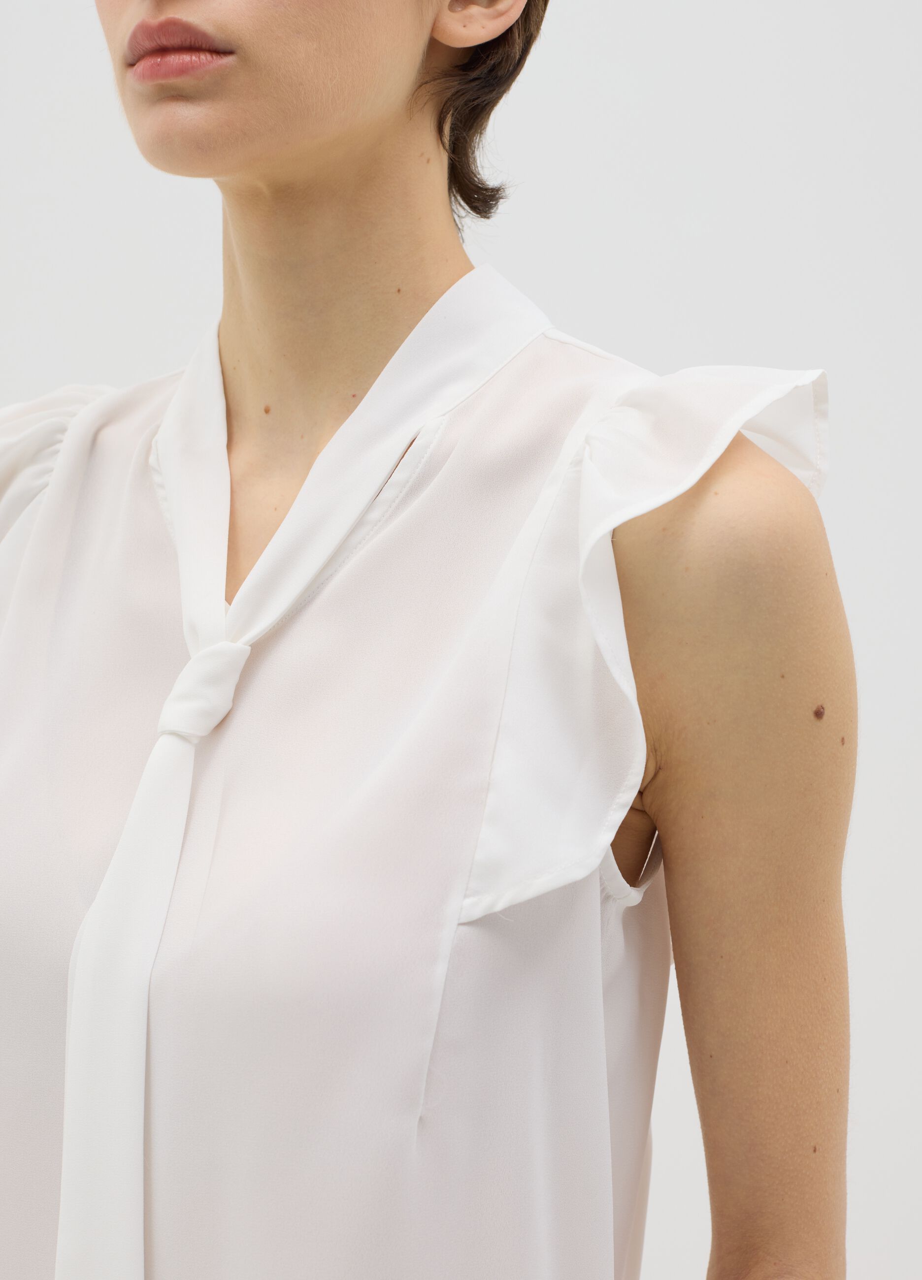 White sleeveless blouse with flounce